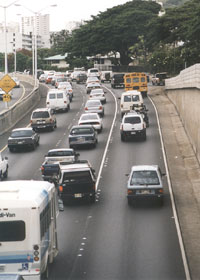 Lane markings on H-1 freeway, with raised reflectors between the travel lanes, and a solid line plus the raised reflectors between the center and right lanes approaching the on-ramp