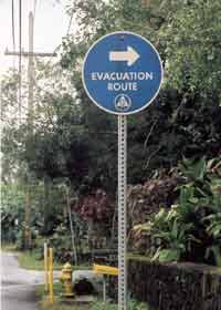 Evacuation route sign near Hilo waterfront, pointing right away from the shore; includes old-fashioned Civil Defense symbol