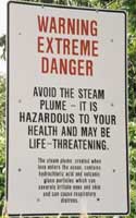 Warning sign: 'Warning | Extreme | Danger | Avoid the steam | plume - It is | hazardous to your | health and may be | life-threatening | The steam plume, created when | lava enters the ocean, contains | hydrochloric acid and volcanic | glass particles which can | severly irritate eyes and skin | and can cause respiratory | distress'