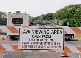 Closeup of sign on barricade in front of tollbooth trailer: 'Lava viewing area | Open from | 12:00pm to 8:15pm | Entry prohibited after 8:15pm | Gate will be locked after 10:00pm'