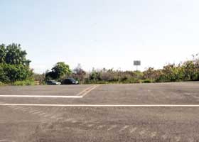 Paved segment of access road, at intersection with paved side road with two cars parked on it