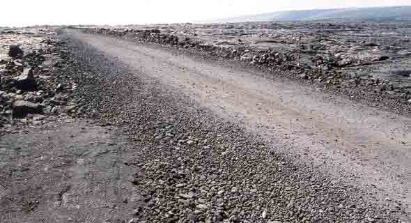 One-lane gravel road through field of pahoehoe lava