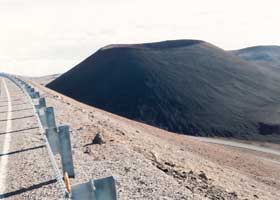 Large black cinder cone alongside road