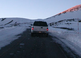 SUV driving through path cleared through a few inches of snow