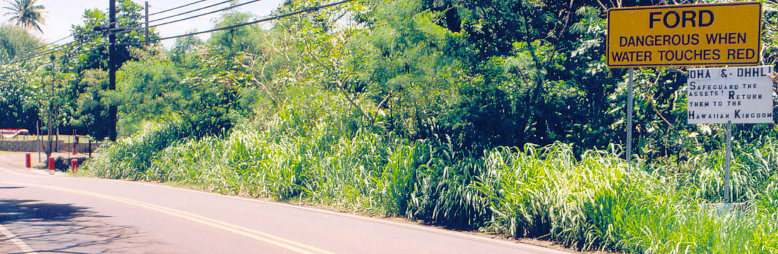 Ford crossing warning sign on far right, with crossing at far left with red markings on concrete posts to indicate hazardous water levels; unofficial sign beneath: 'OHA and DHHL! Safeguard the Assets! Return Them to the Hawaiian Kingdom'