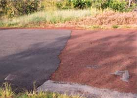 Closeup of transition from old red to new black pavement, with new pavement on left