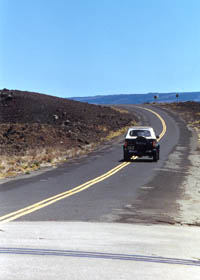 Truck straddling center line of narrow Saddle Road through Army base