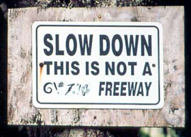 Unofficial sign on dirt road: 'Slow Down, This Is Not A @\#%! Freeway'