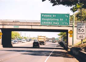 Overhead sign with distances to next three exits, along with 50mph/40mph speed limit sign, and 14ft6in low-clearance sign