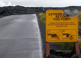 Chain of Craters Road covered with lava beyond this point, as of January 2005; damaged sign warning of dangers of walking onto unstable lava formations